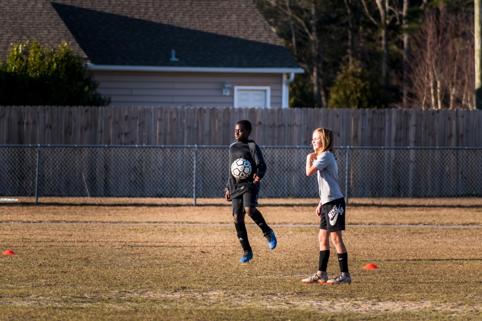 Due ragazzini giocano a calcio in un campo