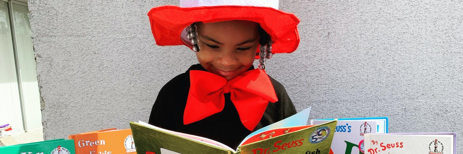 Bambina che legge un libro con un travestimento da Dr. Seuss