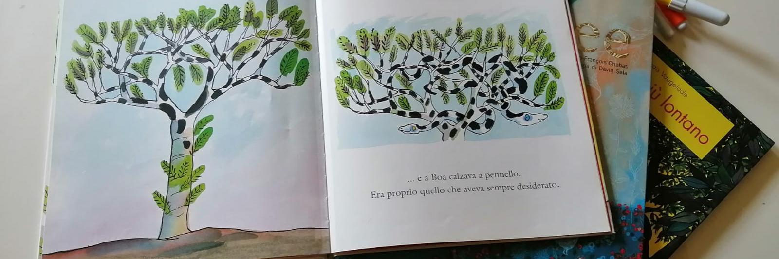 Libro illustrato aperto sul tavolo (c'è disegnato un albero). Accanto altri libri e pennarelli colorati.