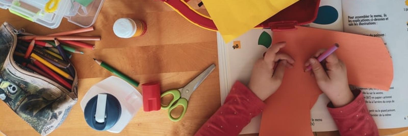 Bambino realizza un lavoretto con cartoncini e matite 