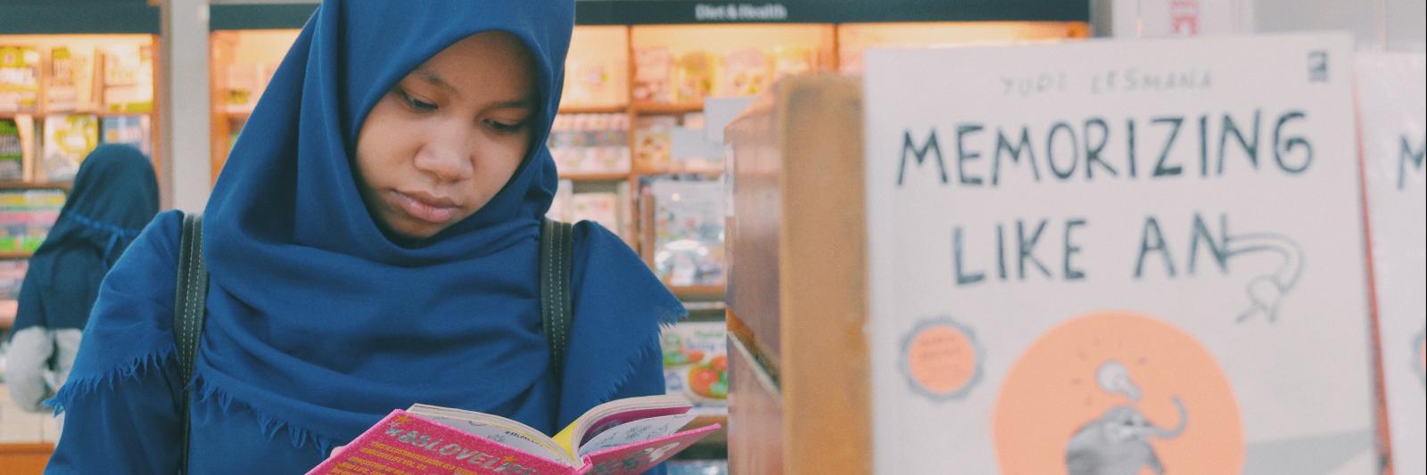 Una ragazza legge un libro davanti ad una libreria