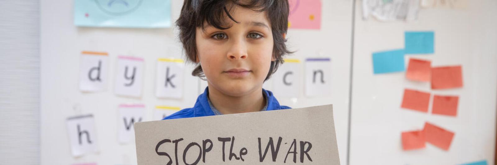 Bambino con cartello "Stop the War on children"