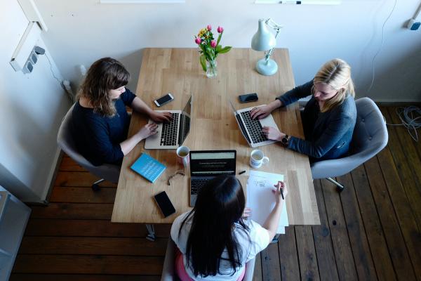 Tre ragazze che scrivono ognuna su un computer sedute attorno ad un tavolo