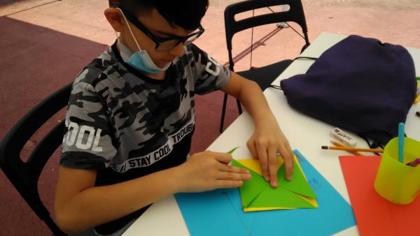 Un bambino piega gli angoli di alcuni cartoncini colorati.
