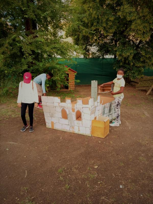 Bambini che giocano con un castello di cartone.