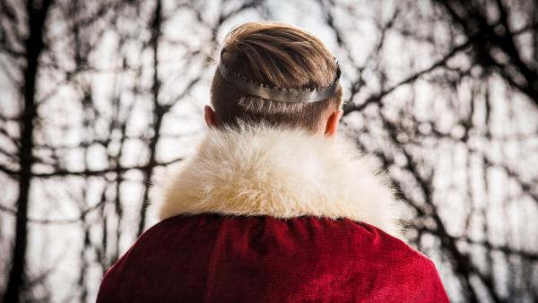 Un ragazzo vestito da re, girato di spalle (non si vede in volto)