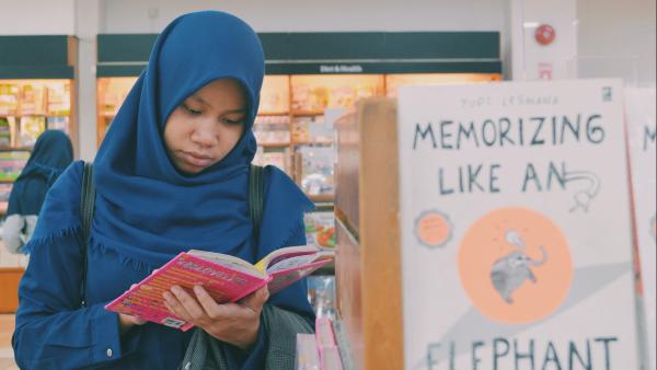 Una ragazza legge un libro davanti ad una libreria