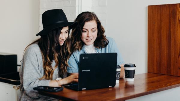 Due ragazze scrivono insieme al computer