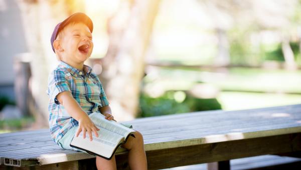 bambino che ride con in mano un libro