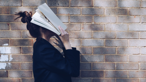 Una ragazza si copre il volto con un libro